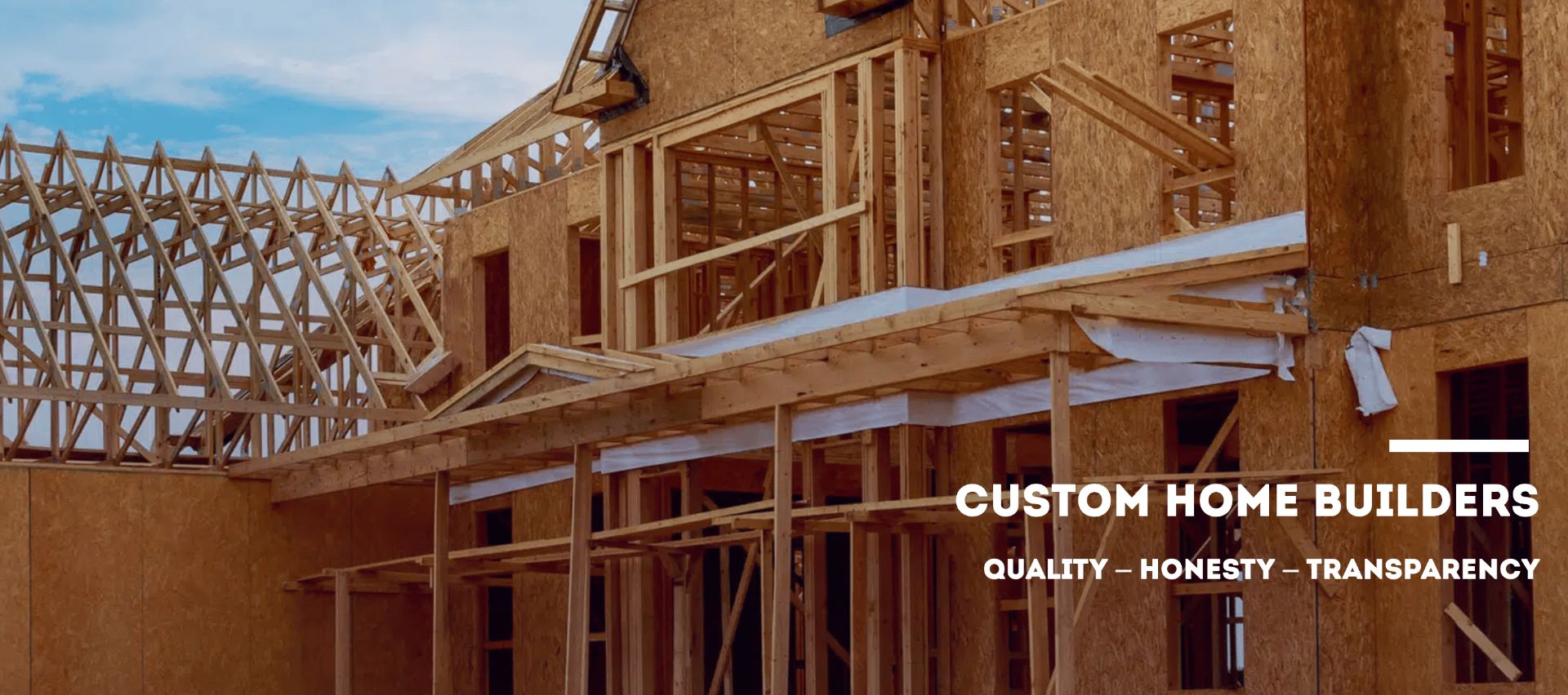 Custom home under construction with exposed wooden framing and trusses, showcasing the early stages of a new build.