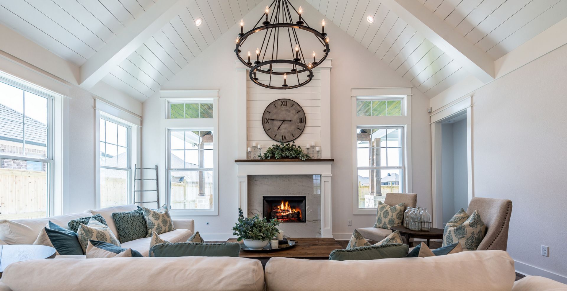 Modern farmhouse living room with vaulted shiplap ceiling, large windows, a cozy fireplace, and stylish neutral décor.