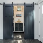 Modern farmhouse entryway featuring black sliding barn doors, white walls, and a mudroom with built-in storage, designed by Sayers Contracting.